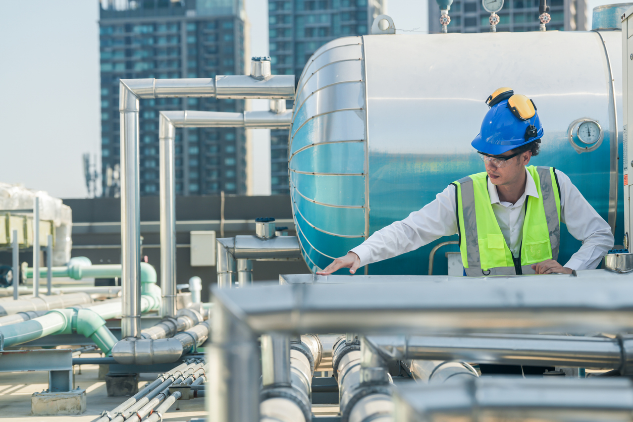 Maintenance worker inspects fixd assets on roof of building | Maintenance