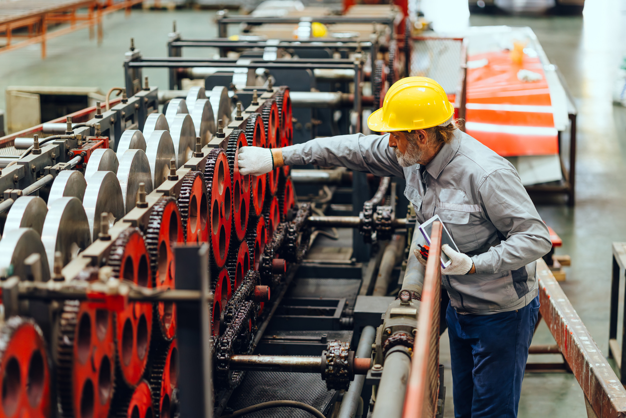 Maintenance worker on plant floor inspects machine | Maintenance