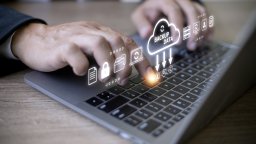 Hands typing on a laptop keyboard with digital icons hovering above, showcasing "Backup Data" and symbols for security and cloud storage