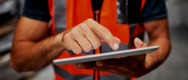 Safety & compliance worker is vest and holding tablet | CMMS