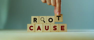 A finger places down blocks to spell out root cause