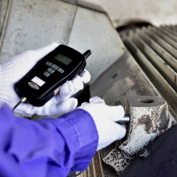 Technician hand holds testing machine to equipment | CMMS