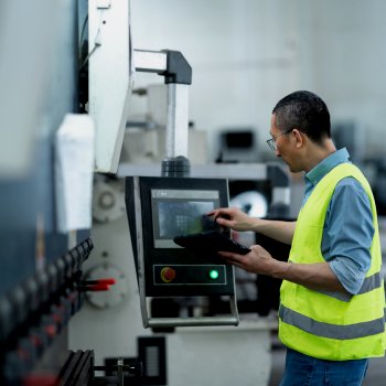 Man in reflective vests holds tablet while resetting machine | Maintenance