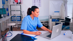 Doctor sits at desk looking at computer | CMMS