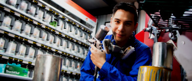 Young man looking at camera and holding paint sprayer wearing respirator
