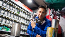 Young man looking at camera and holding paint sprayer wearing respirator