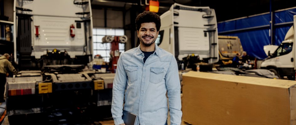 Planning coordinator of small fleet maintenance stands on shop floor with mobile device | CMMS