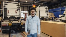 Planning coordinator of small fleet maintenance stands on shop floor with mobile device | CMMS