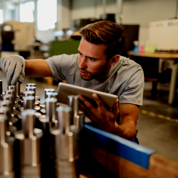 Technician inspects production line holding tablet